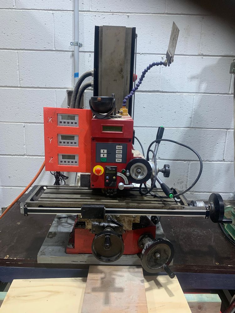 A Sieg X3 mill is packed up ready to be moved to a new spot in the workshop.    The head is lowered all the way to the bed.