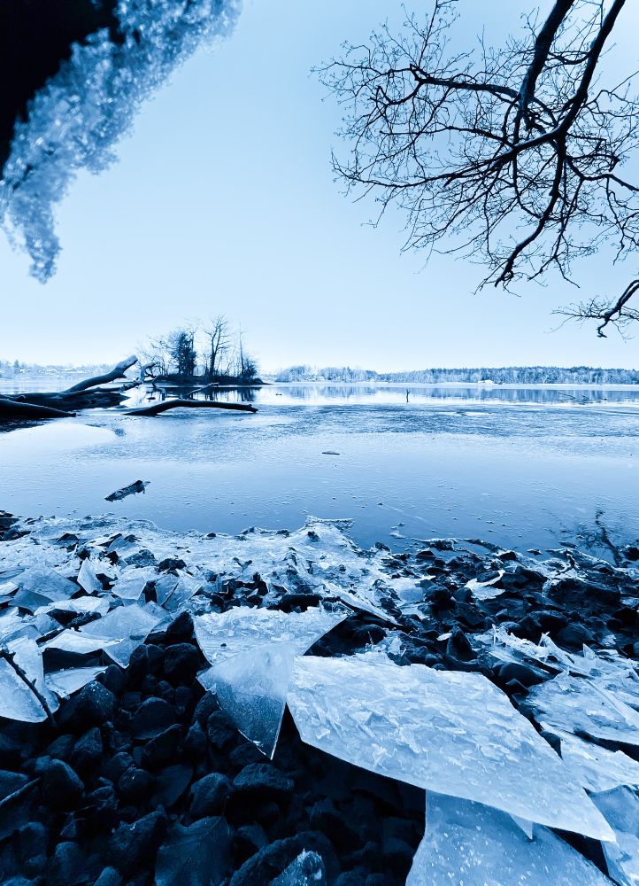 Blick auf einen halb zugefrorenen See, am Ufer Eisschollen.