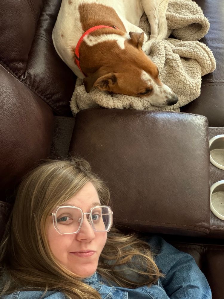 Me and my dog laying on a brown leather couch, I’m looking at the camera my dog is watching the tv 