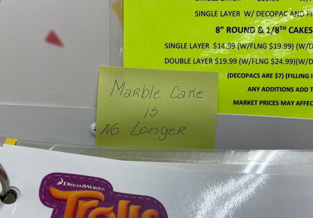 A sticky note on a cake display which say “marble cake is no longer”.

That’s the whole thing. It literally ends there. It’s not like some of the sticky note is behind something and blocks the final word “available” or something.

It just says, in total, that marble cake is no longer. 