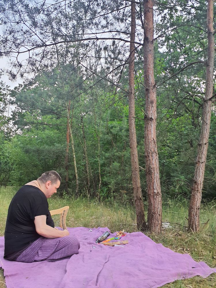 Me sit ting on a blanket with a harp next to me and Infront of me arranged ritual tools 