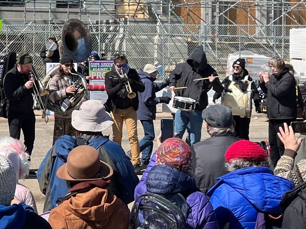 Trombone, tuba, trumpet, drum and flute players blocking the view of some hateful bullshit so-called Christians.