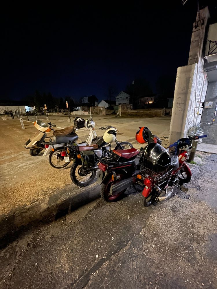 Scooters/mopeds parked in a row in a dark parking lot