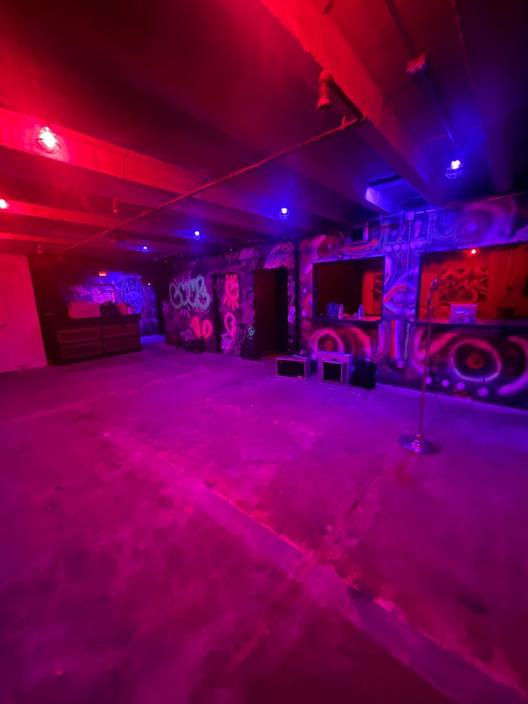 A concrete basement with pink, purple, and blue lighting