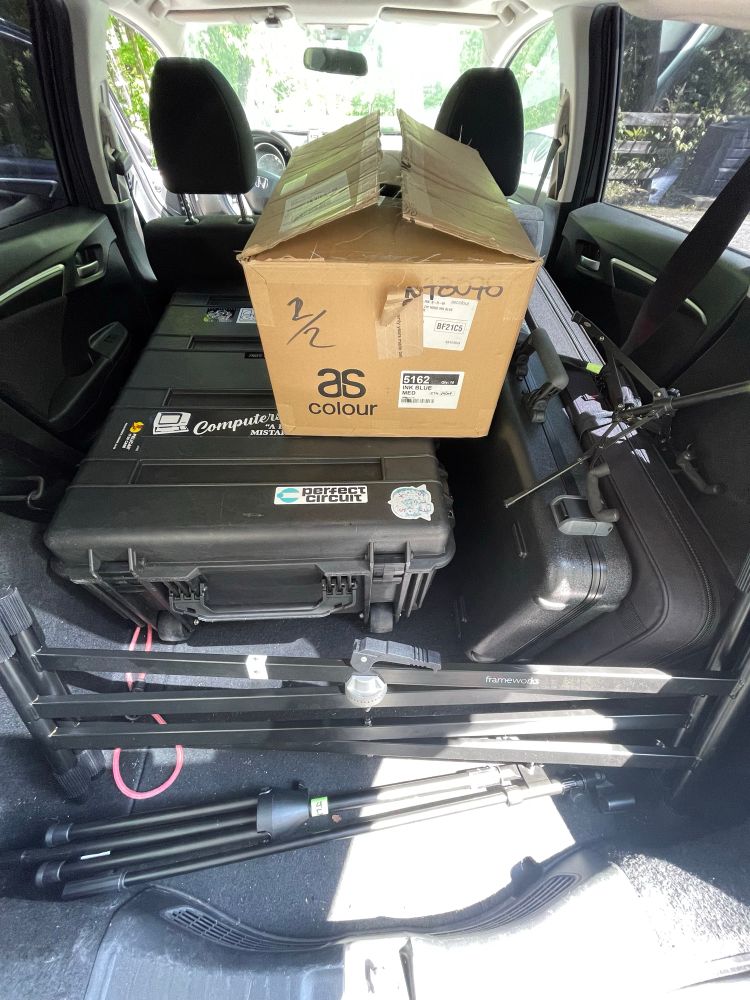 The back of a hatchback full of road cases and a box of merch