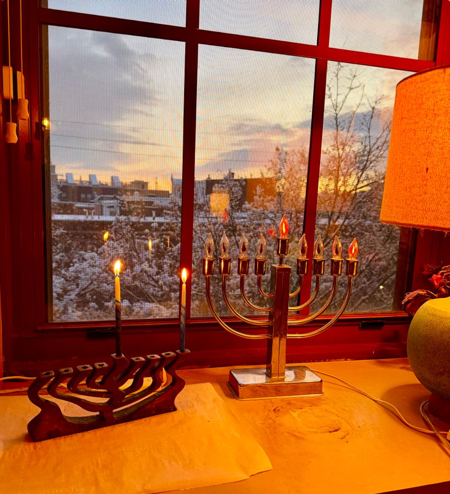 Two menorahs lit for the first night of Chanukah, one with candles, one electric. 