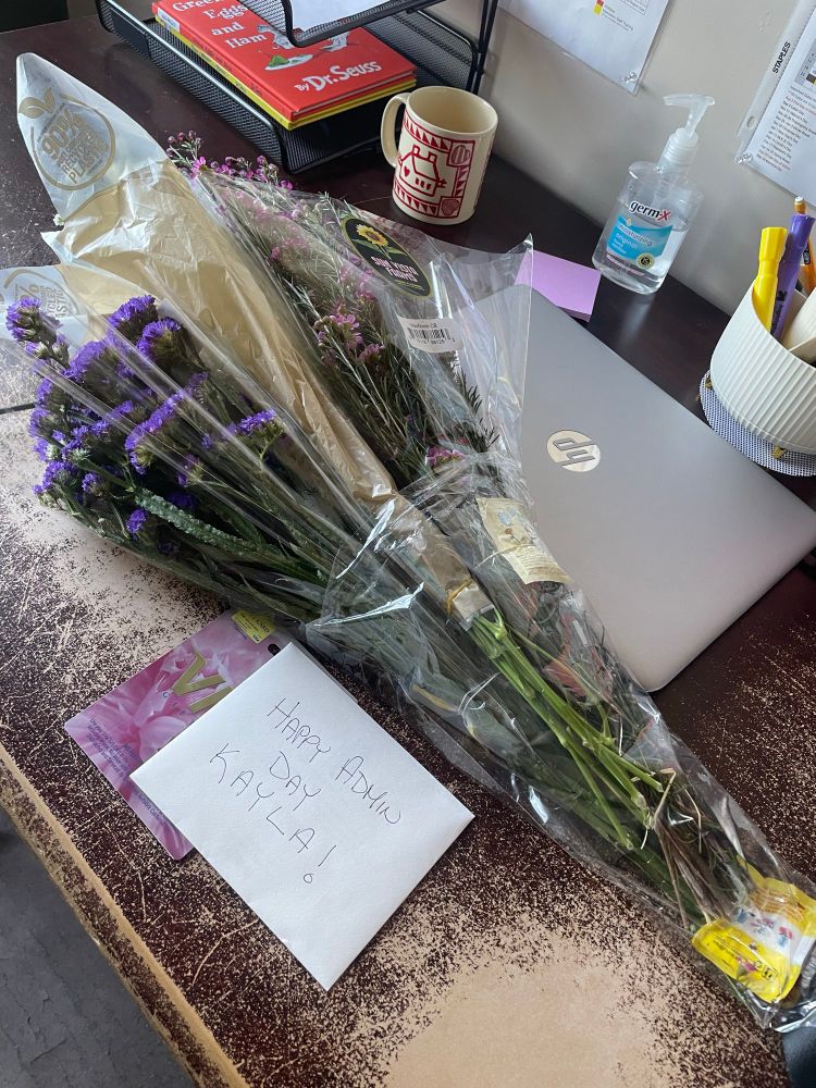 Flowers and card on desk that read “happy admin day Kayla!”