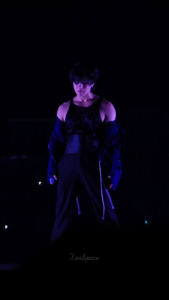 Taemin on stage, jacket slightly off his shoulder.