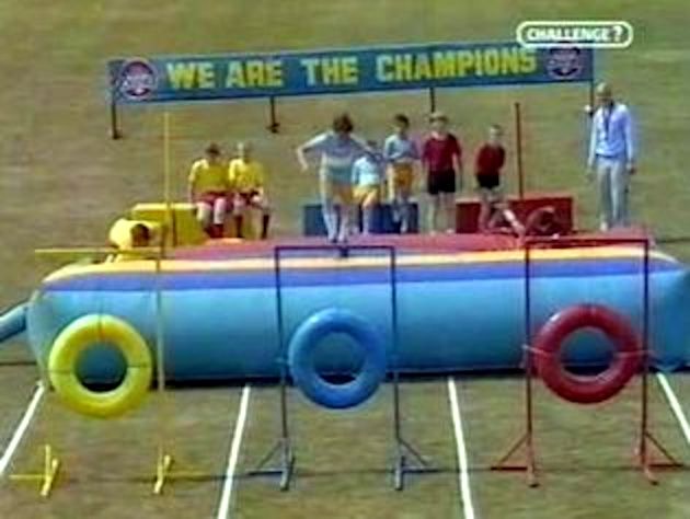 Still from the children's TV show We Are The Champions in which teams of kids are running an obstacle course.