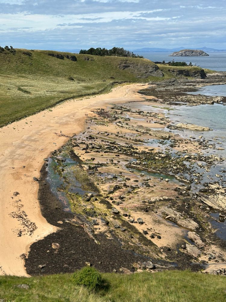 Beach, rock and shingles - beautiful hills in the background behind blue, clear sea. 