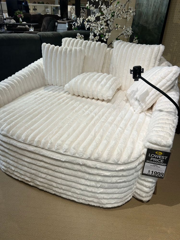 Huge white fluffy round chair (?) with a price tag of $1999 in a furniture store.