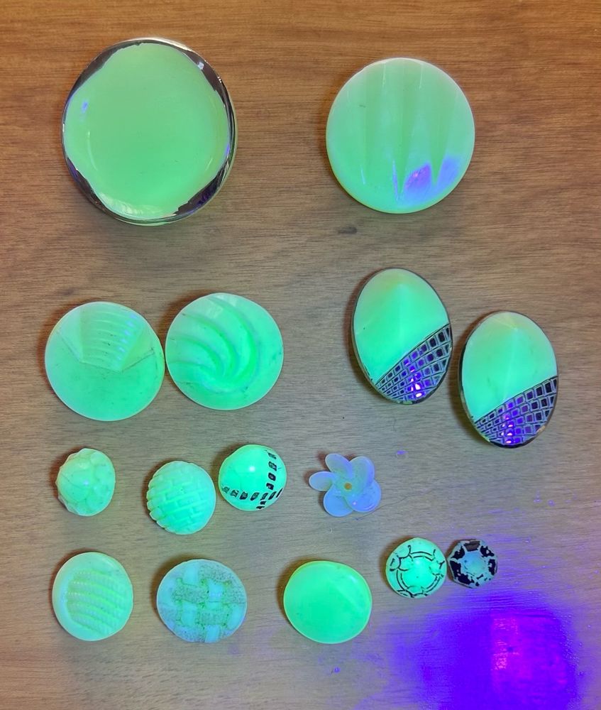 Sewing buttons glowing green under the light of a black light.