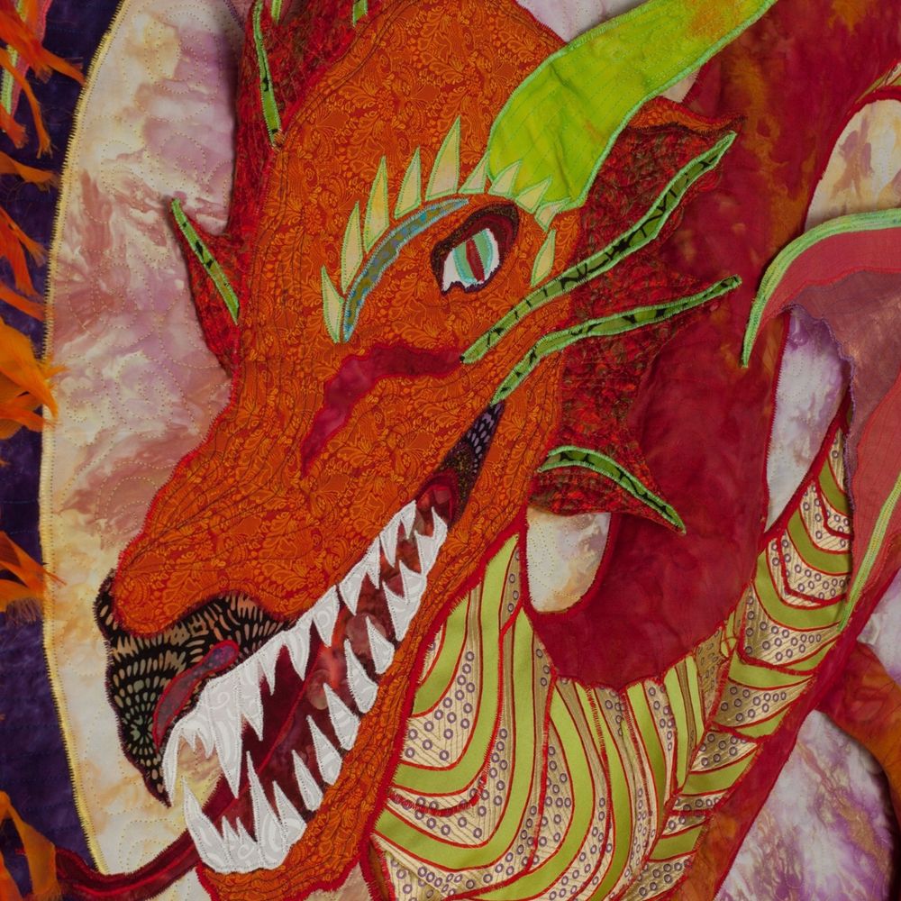 Orange silk fabric dragon with green silk fabric underbelly and large white teeth.