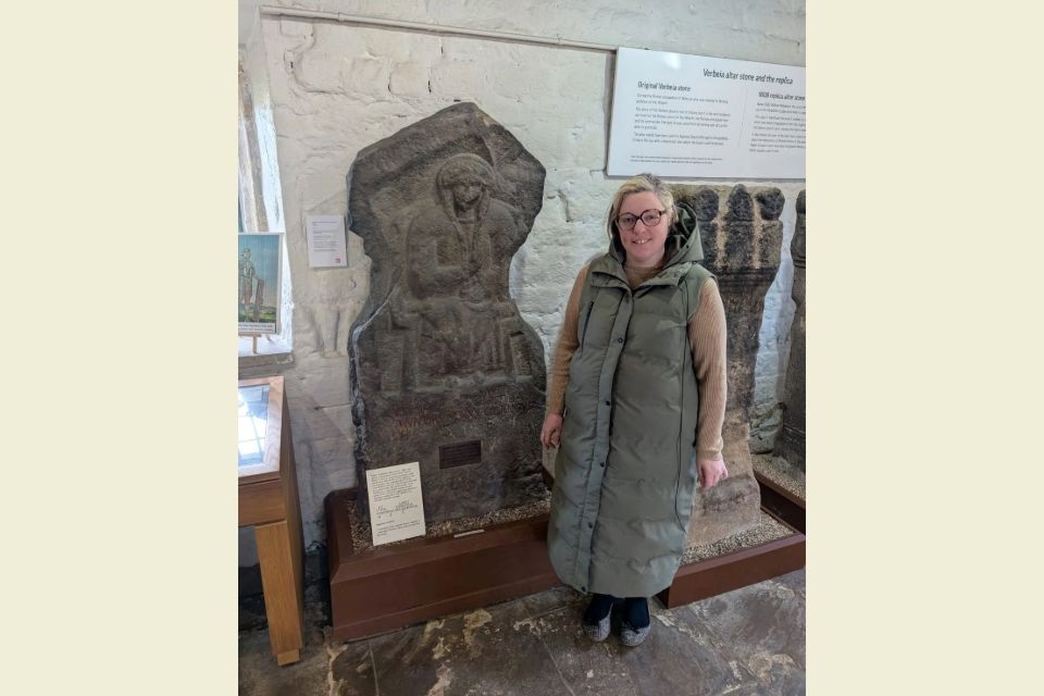 Charlotte Bell standing next to some Roman stonework.