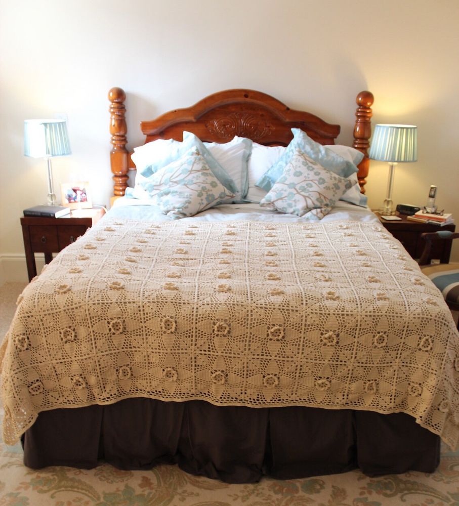 A white granny square bed cover: each granny square has elevated flower in the centre. 