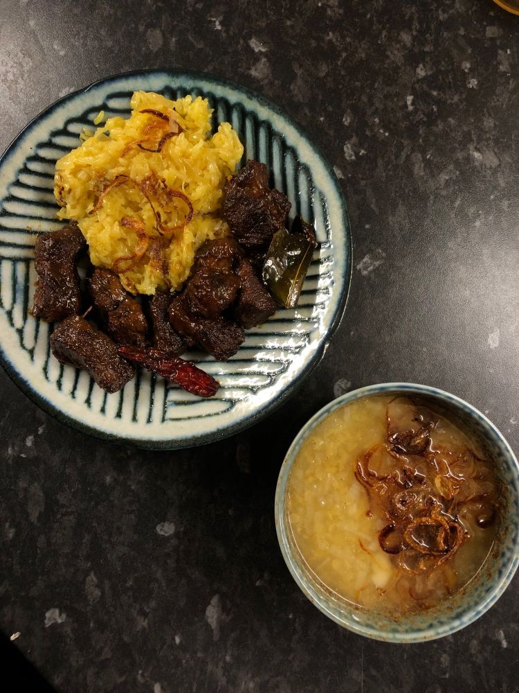 A picture of three Burmese dishes. Firstly, lime-leaf pot roast beef, which is beef braised in a savoury and aromatic sauce until relatively dry. Alongside it is golden sticky rice, glutinous rice steamed with turmeric and browned onion slices. Next to this plate is a bowl of soup made with red lentils, flavoured with onions, garlic and enhanced with a sprinkle of MSG, then topped with crispy fried onions. 
