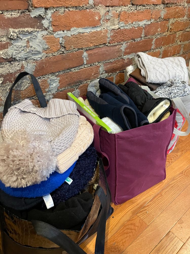 Bags overflowing with winter hats, gloves, scarves, and socks.