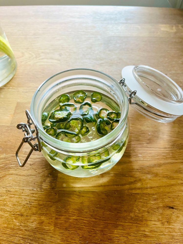 The jar viewed from above with sliced jalapeños floating in simple syrup. 