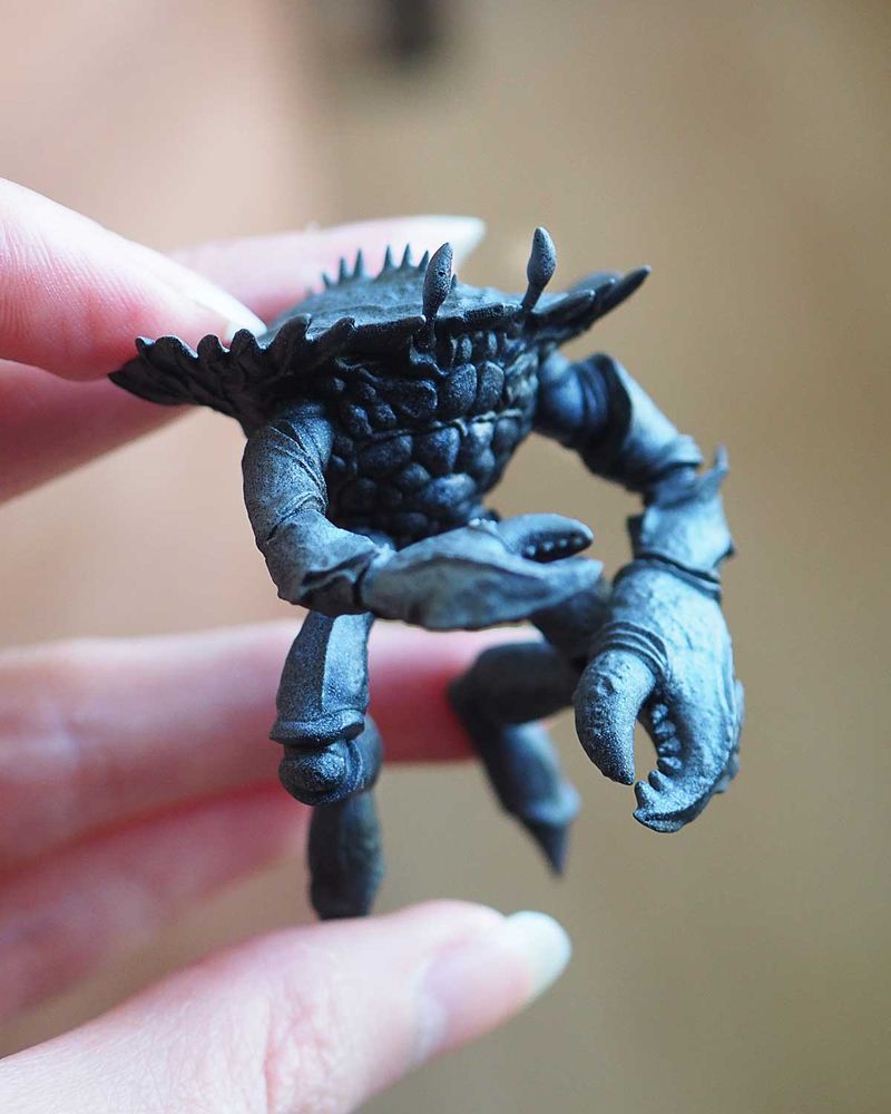Figurine de crabe humanoïde que je tient dans ma main.