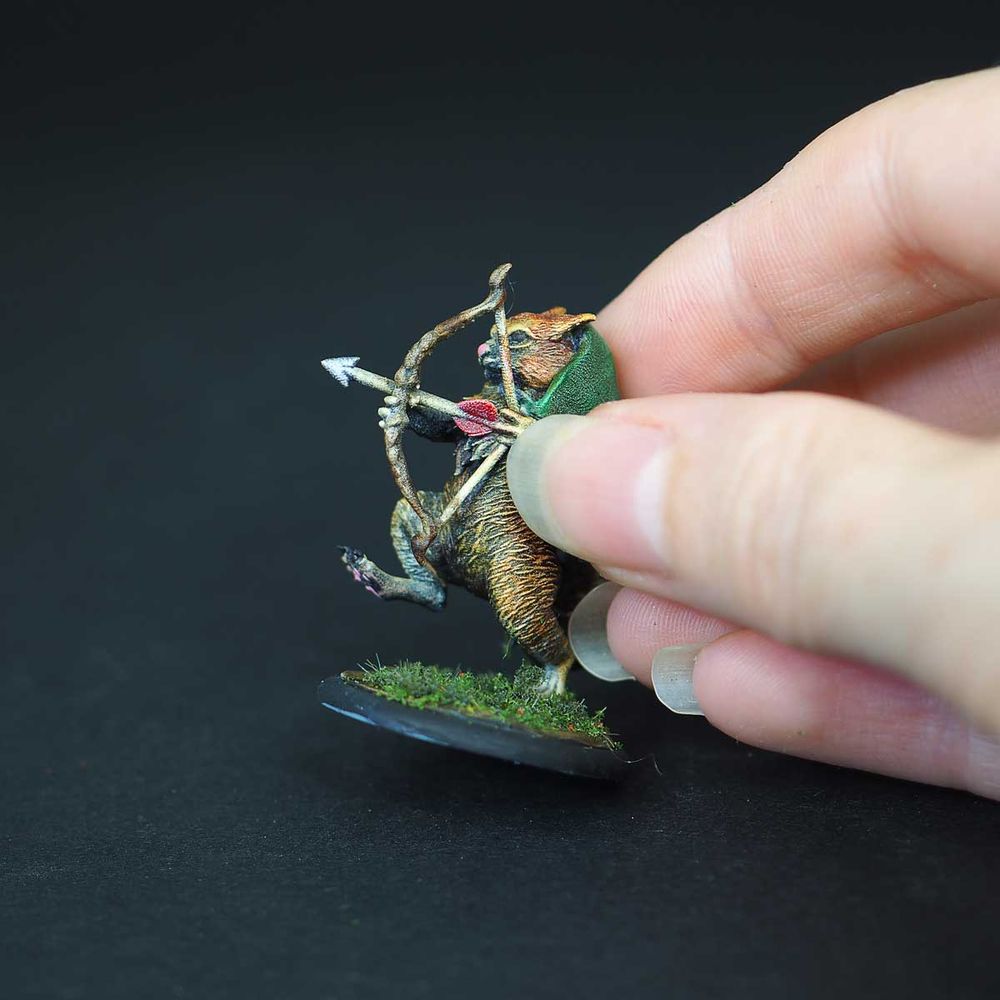 Miniatures écureuil avec un arc et un cape, il est tenu dans une main.