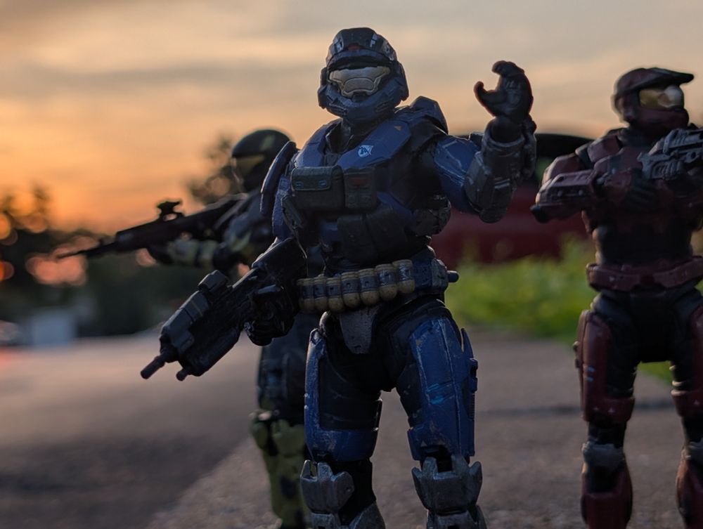 Three Halo Spartans backlit by sunset, standing on a paver block. 
