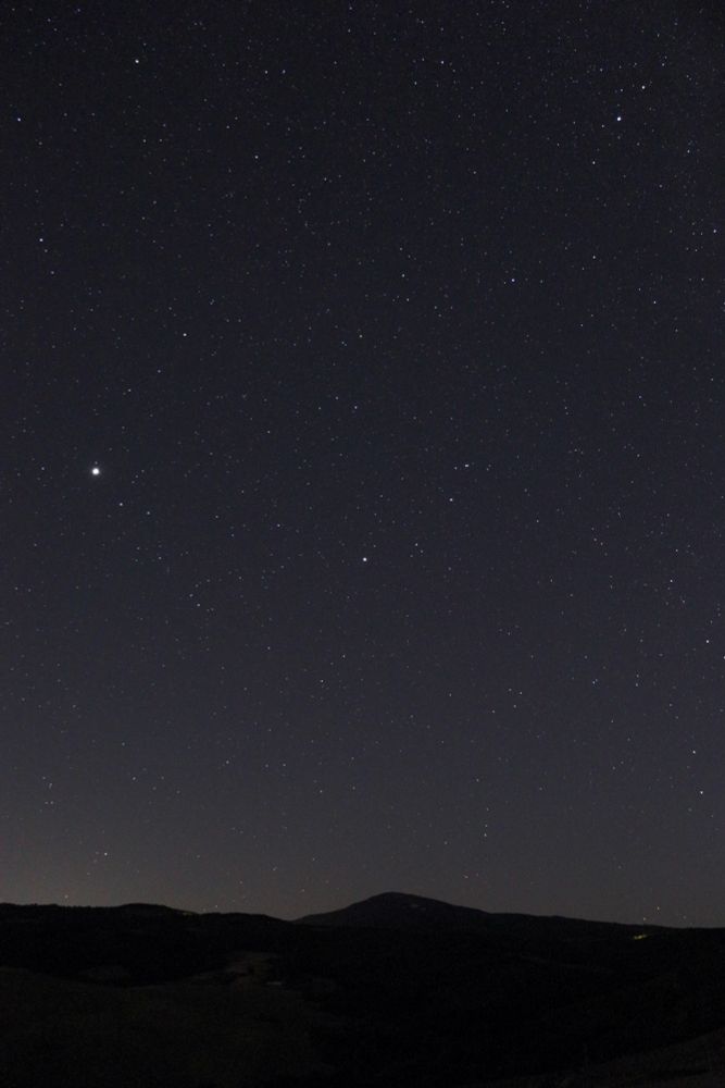 A clear night sky filled with stars. Below, a dark range of hills forms a silhouette against the starry background.

Details: Canon EOS 250D with kit 18mm F4 lens, ISO 1600, 15s.
Location: Val d'Orcia, Italy