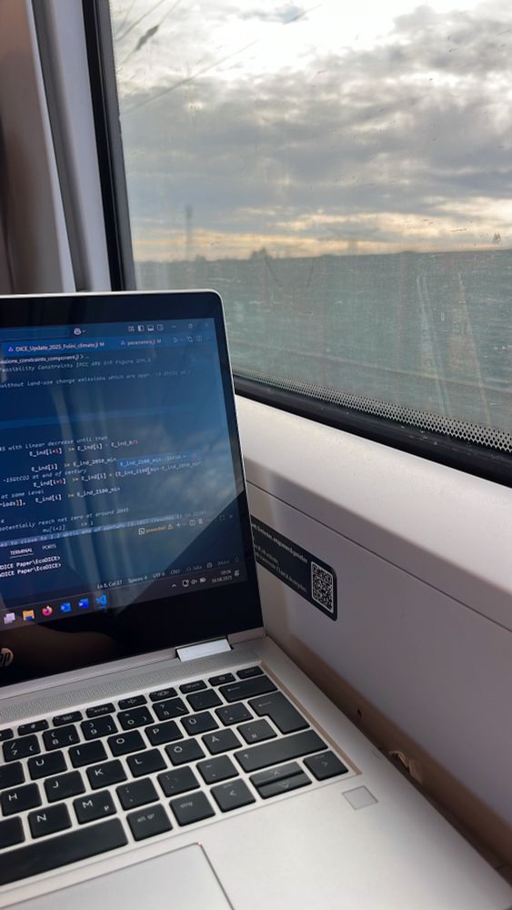 A laptop party seen and a part of the window outside a train