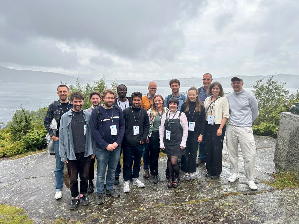 A group of researchers on a hill with a fjord and some mountains in the background