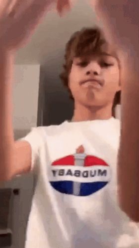 a boy wearing a pepsi t-shirt is making a funny face