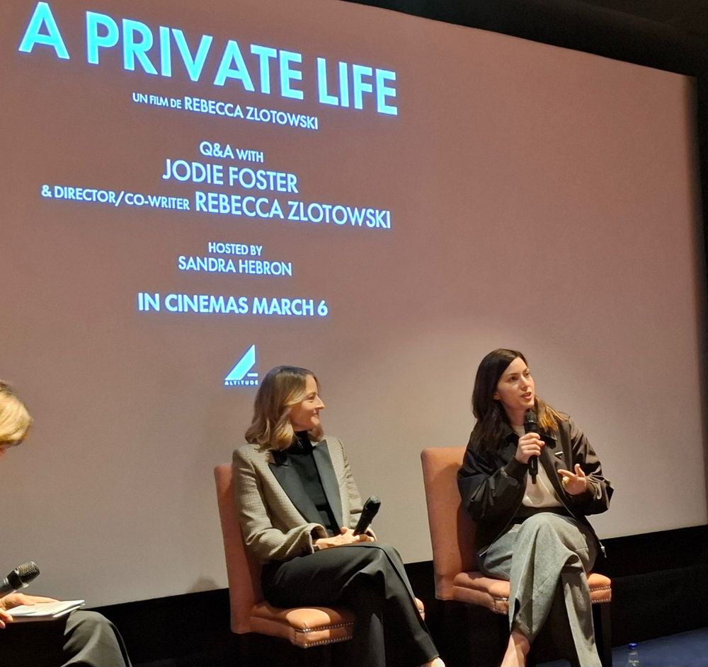 Jodie Foster sits on a chair in front of a cinema screen, holding a microphone ready to take audience questions as she attends a cinema screening of her new film A Private Life.