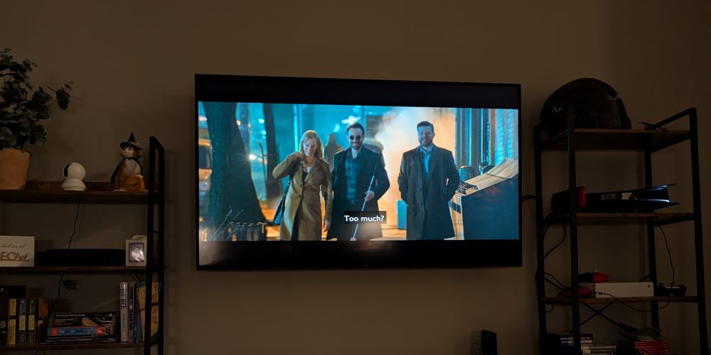 Two shelves with a TV in between them within my living room. The TV has Karen, Matt Murdock, and Foggy on display in episode 1 of Daredevil Born Again. 