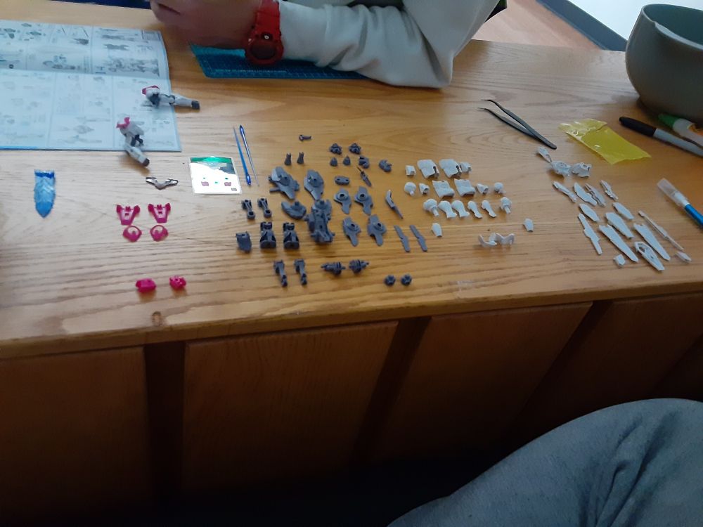 pieces of an unassembled Lfrith Gunpla organized on a table