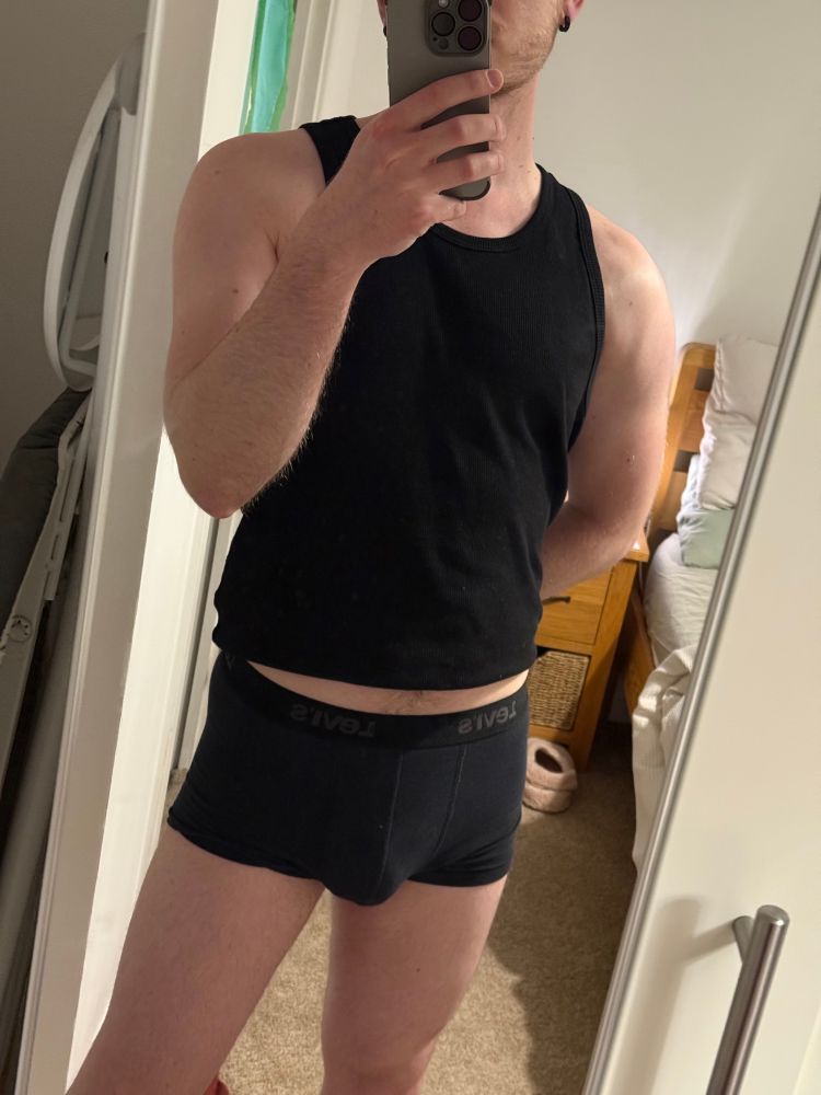Me standing in front of my mirror wearing a black vest top and boxer briefs 