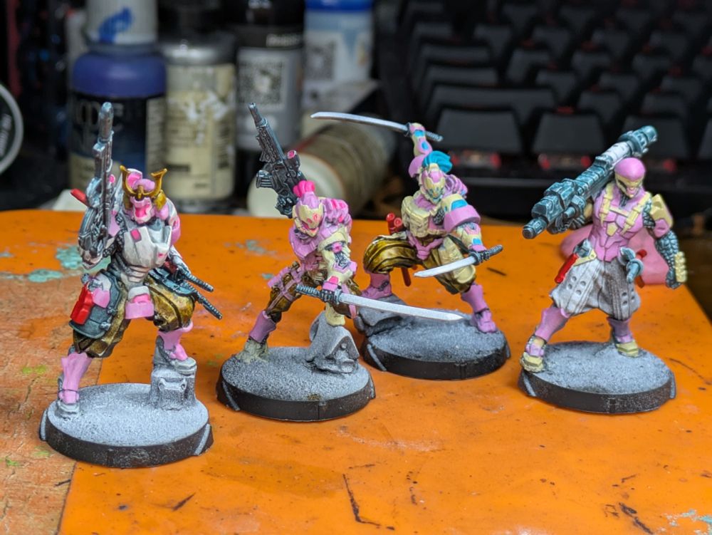 Infinity miniatures from the Shindenbutai faction. Power armored samurai and "totally not a ninja" with thite, sand, and pink armor sporting a variety of weapons. Works in progress painting.