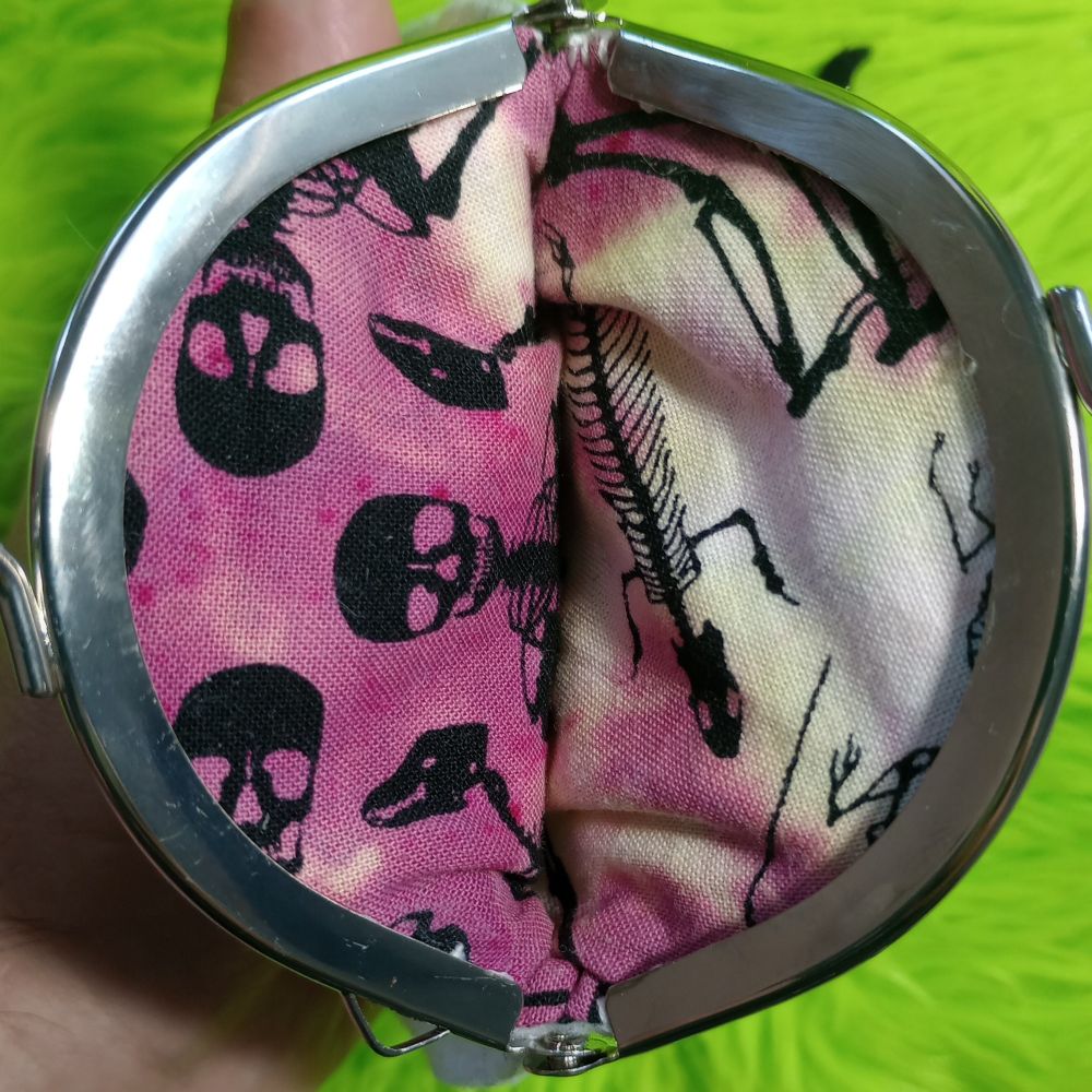 Here's a peek in the lining of the ghost bag. It's a purple and white tie-dyed cotton fabric with a skeleton print. There are human skeletons and some animal skeletons. Perhaps a lizard and a rat skeleton.