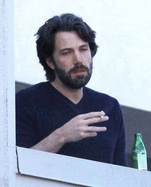 Ben Affleck with a scruffy beard holding a cigarette looking exhausted