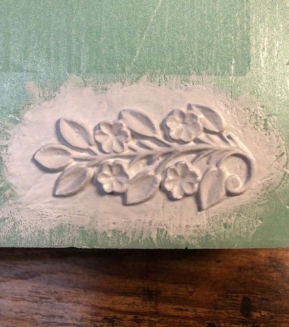 Close up of a 3D floral motif, which has been applied to a foam panel and then painted white.