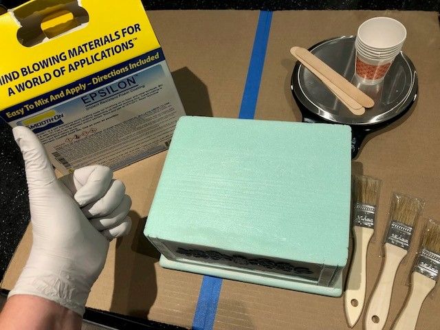 A work-in-progress picture of a decorative box set on a cardboard surface with other supplies set out next to it. The supplies will be used to coat the project in an epoxy coating product.