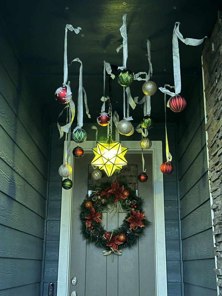 Ornaments hanging in an entry. A wreathe is on the door. 