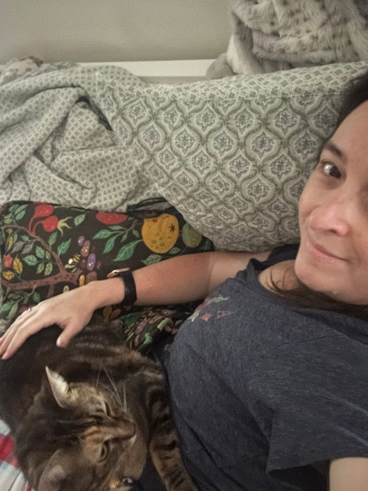 A woman lying down with a cat on her lap