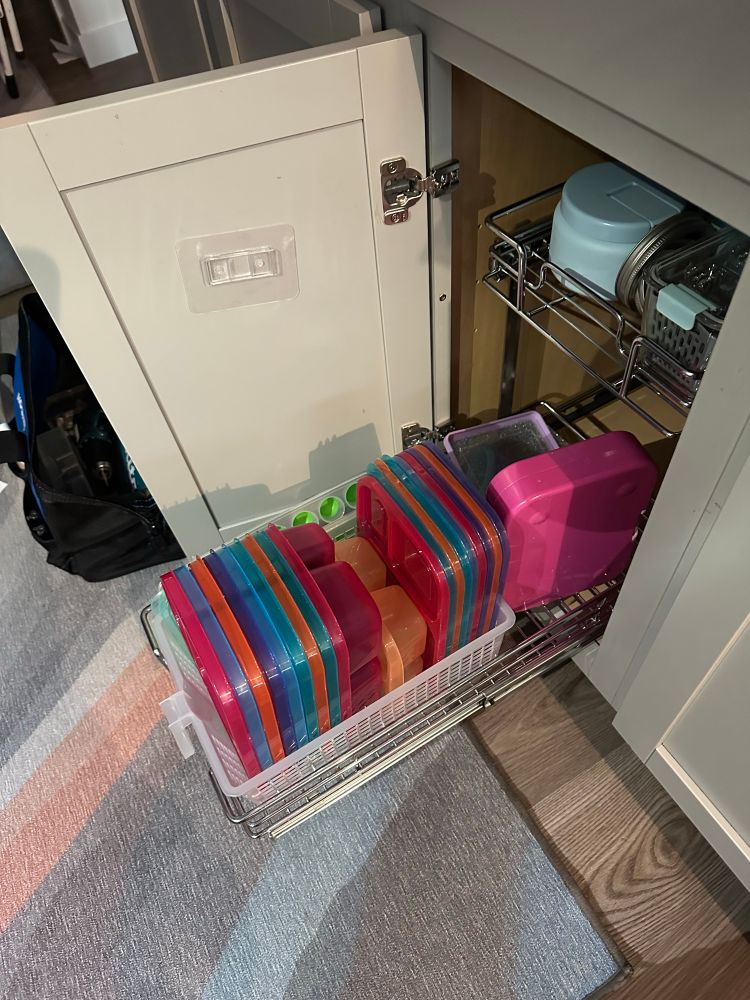 A cabinet drawer full of lunch stuff: plastic Tupperware type containers for packing lunches. 