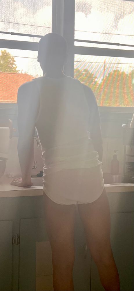 Standing by the sink in the kitchen wearing a white Calvin Klein tank top and white fruit of the loom briefs