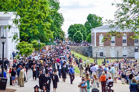 large group of students on a university campus with buildings to the left and right