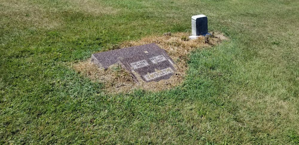 A tombstone that has fallen over You see tombstones that have gotten damaged or have fallen over and since most cemeteries don't repair tombstones they lay there like that 