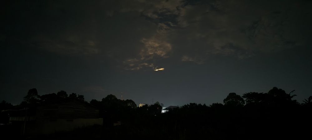 The night sky, with a dash of light looking like a strip of cloud as rhe moon prepares to rise....the ground is a deep shadow, 