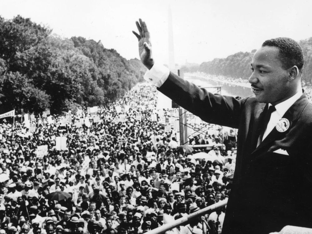 Black and white historic news photo of Martin Luther King addressing a vast crowd of civil rights supporters on the Mall in Washington, D.C. 