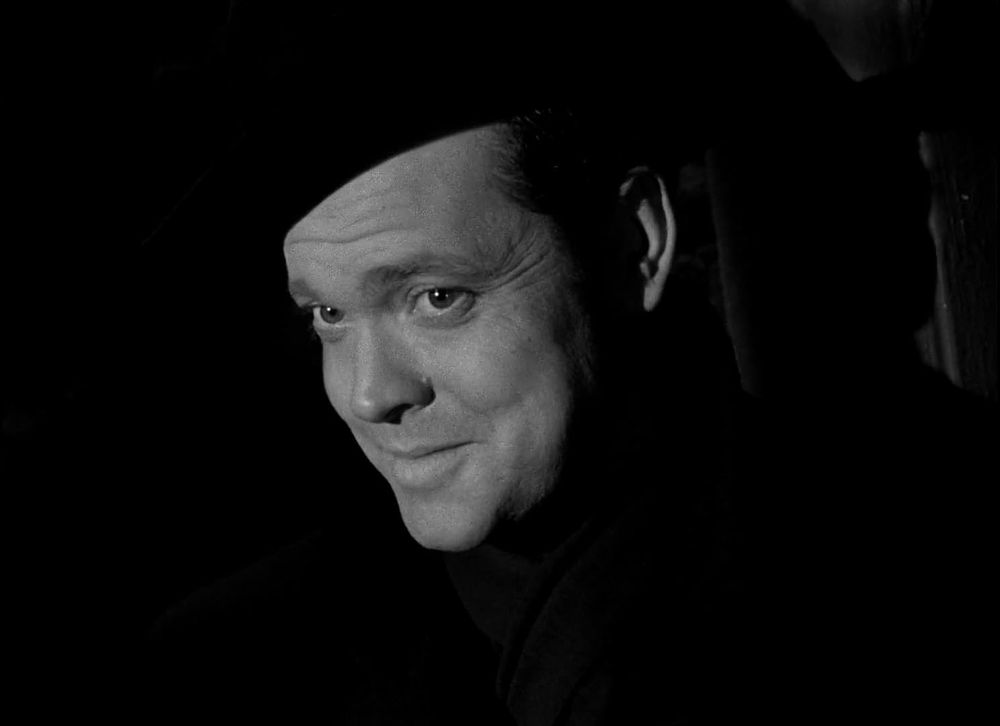 A man’s face rises out of the darkness. He is Orson Welles as Harry Lyme, postwar Berlin black marketer in the 1949 film masterpiece, “The Third Man.” His smile is disarming, ambiguous, and potentially lethal. 