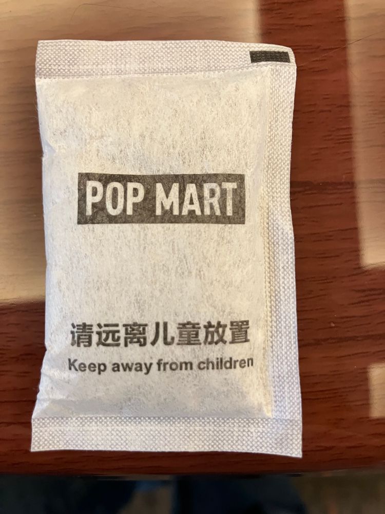 Desiccant bag with “POP MART- Keep away from children” written on face