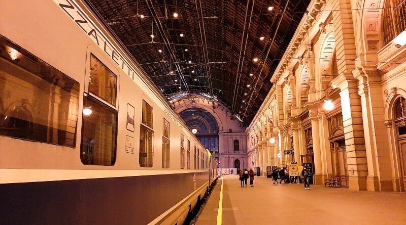 View down a well lit railway platform with a sleeper train alongside