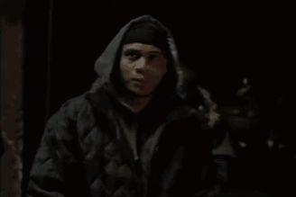 a man wearing a hooded jacket is standing in the dark